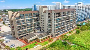 A multi-story hotel with balconies, a covered outdoor area, and a swimming pool.