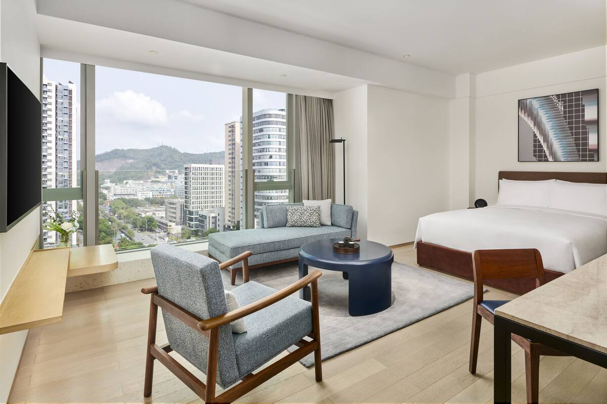 Une chambre d’hôtel moderne équipée d’un grand lit, d’un canapé, d’une table à manger et d’un téléviseur.