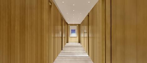 A corridor with a patterned floor, wooden walls, and a ceiling with recessed lighting.