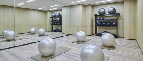 A gym with exercise balls on mats and a mirrored wall.