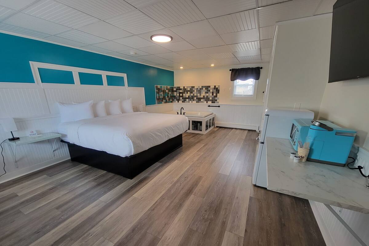A bedroom with a large bed, a small table, a microwave, and a coffee machine.