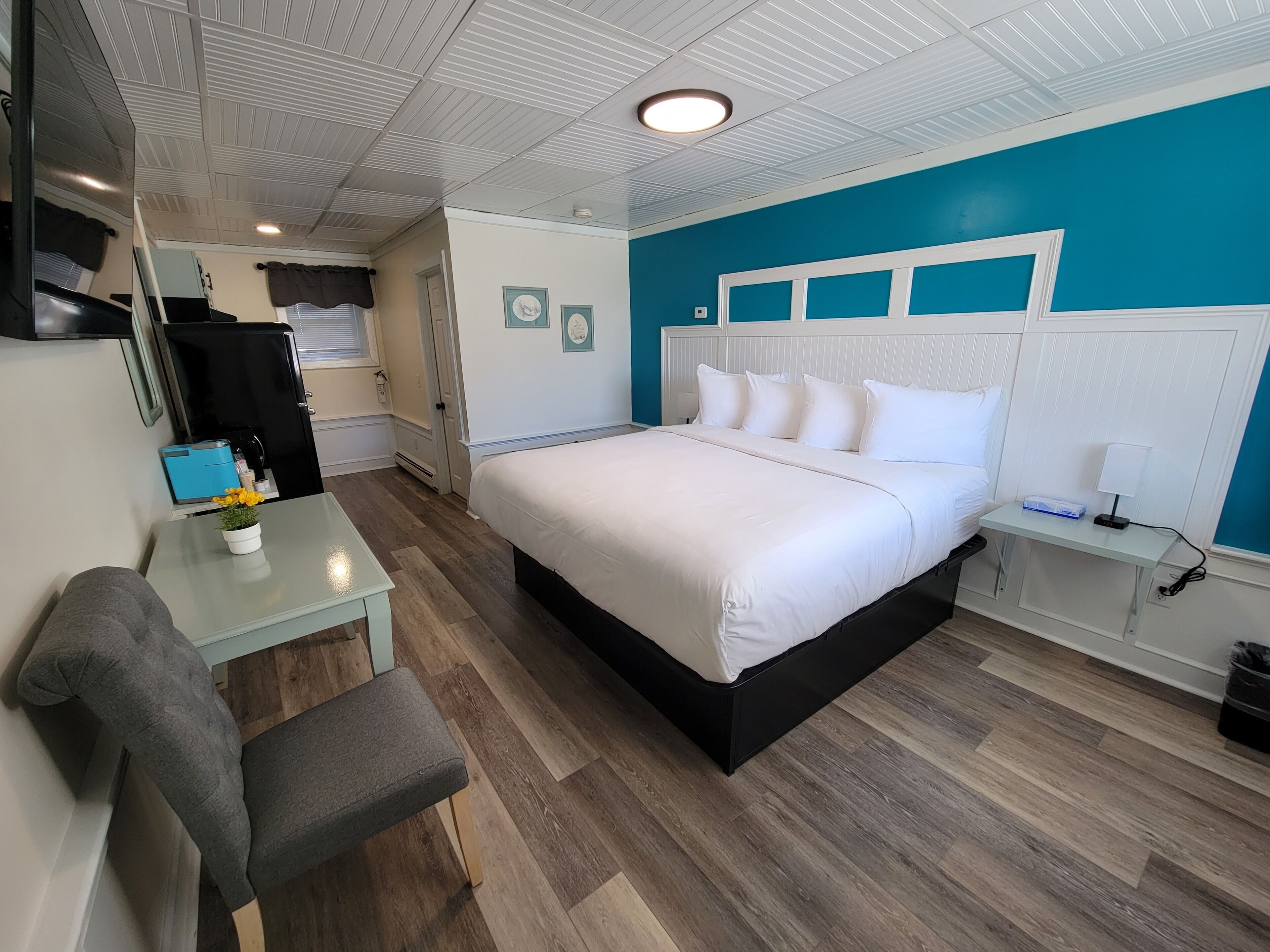 A bedroom with a bed, bedside table, lamp, and a small desk with a chair.