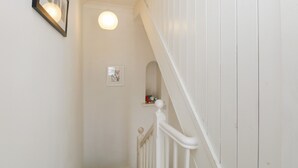 A white staircase with a handrail, a framed picture on the wall, and a light fixture above. - The Postmasters House (Windermere)
