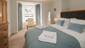 A neatly arranged bedroom with a bed, a chair, and a desk. - The Postmasters House (Windermere)
