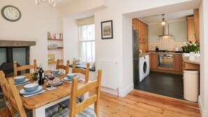 A modern kitchen with wooden cabinets, a built-in oven, and a washing machine. - The Postmasters House (Windermere)