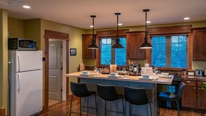 A kitchen with wooden cabinets, a central island with bar stools, a refrigerator, and a microwave. - Mountain Studio - luxury finishes in upscale neighborhood, e-bikes included! (Bozeman)