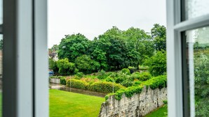 Vista de un jardín exuberante con un muro de piedra y un pequeño canal.