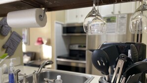 Una cocina con un lavamanos de acero inoxidable, dispensador de toallas de papel, dispensador de jabón y un organizador de utensilios.