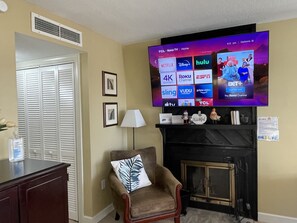 Un soggiorno con una TV a schermo piatto montata a parete che mostra diversi servizi di streaming.