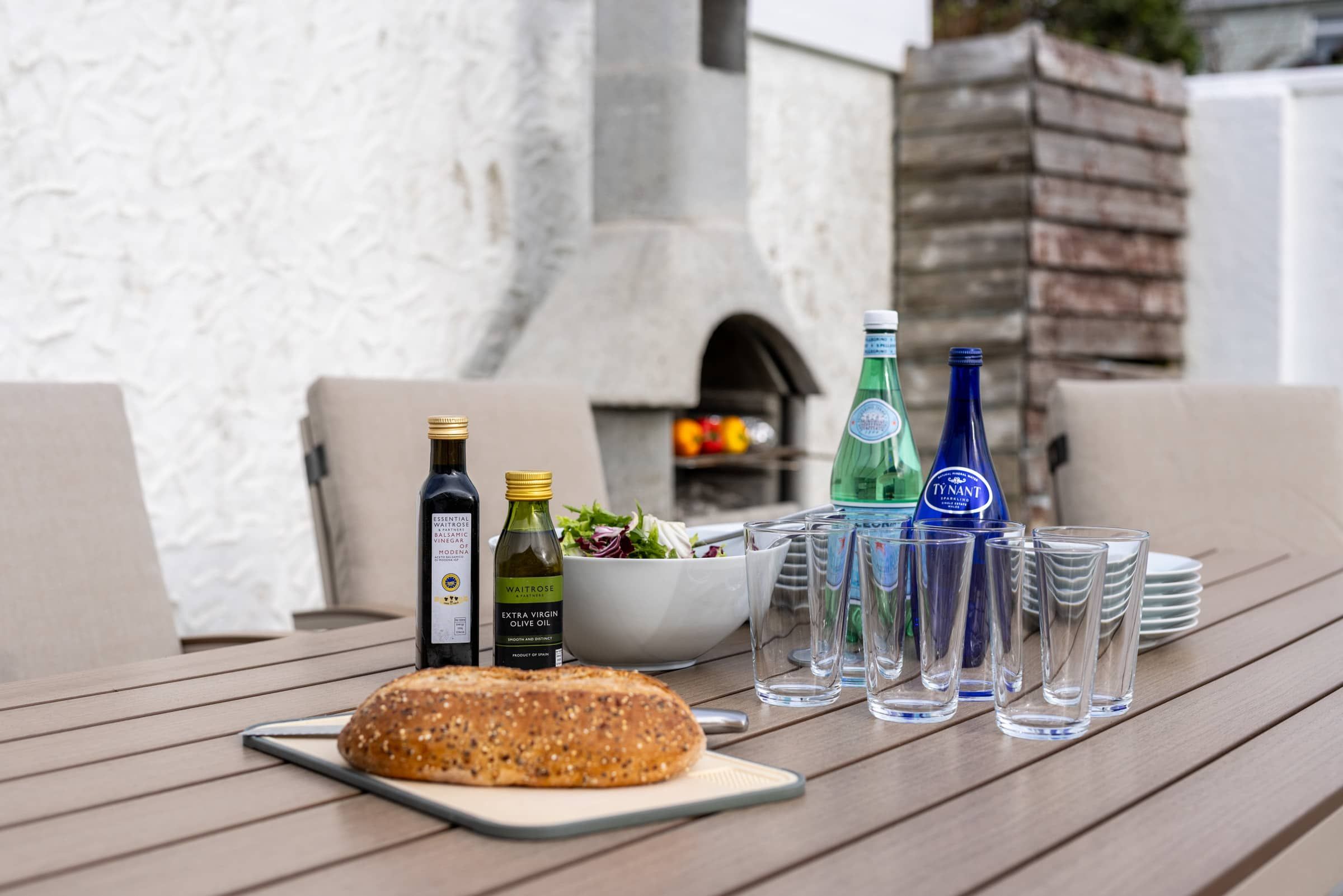 Ein Tisch mit Brot, Olivenölflaschen und Gläsern, der eine Mahlzeit andeutet.