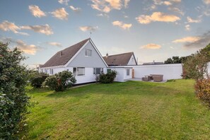 Enclosed rear lawned garden wrapping around the house, safe outdoor space for two pets and children at pet-friendly holiday home in Rhosneigr, Anglesey