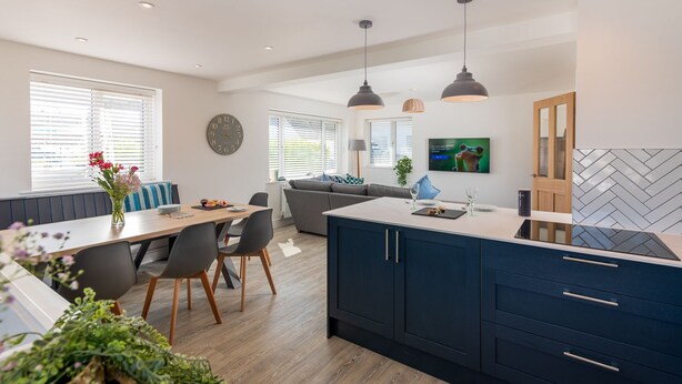 Een moderne keuken met donkere kastjes, een centraal eiland en hanglampen.