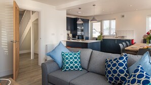 Een moderne keuken met donkere kastjes, een centraal eiland en hanglampen.