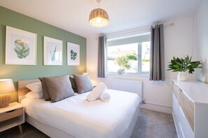 Double bedroom with sage green feature wall and botanical prints, stylish accommodation at holiday home sleeping eight in Rhosneigr, Anglesey