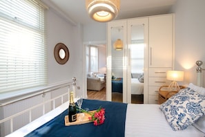 A hotel room with a bed, bedside table, lamp, and a view of the adjacent room. - Bryn Awel Bach: Two bedroom holiday apartment in Rhosneigr (Rhosneigr)