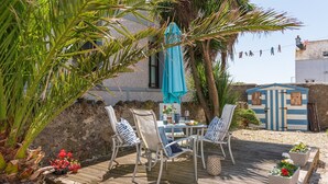 A patio with a table and chairs, a small shed, and a clothesline. - Bryn Awel Bach: 2-Bed Apartment in Central Rhosneigr | Managed by Anglesey Holiday Lettings (Rhosneigr)