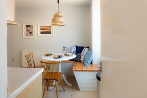 A compact kitchen with a dining table, chairs, and a hanging light fixture. - Bryn Awel Bach: Two bedroom holiday apartment in Rhosneigr (Rhosneigr)