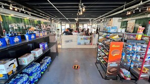 An indoor shopping area with shelves stocked with beverages like Bud Light and Corona, a display of Reese's, and a counter area. - New Orleans RV Resort & Marina (New Orleans)