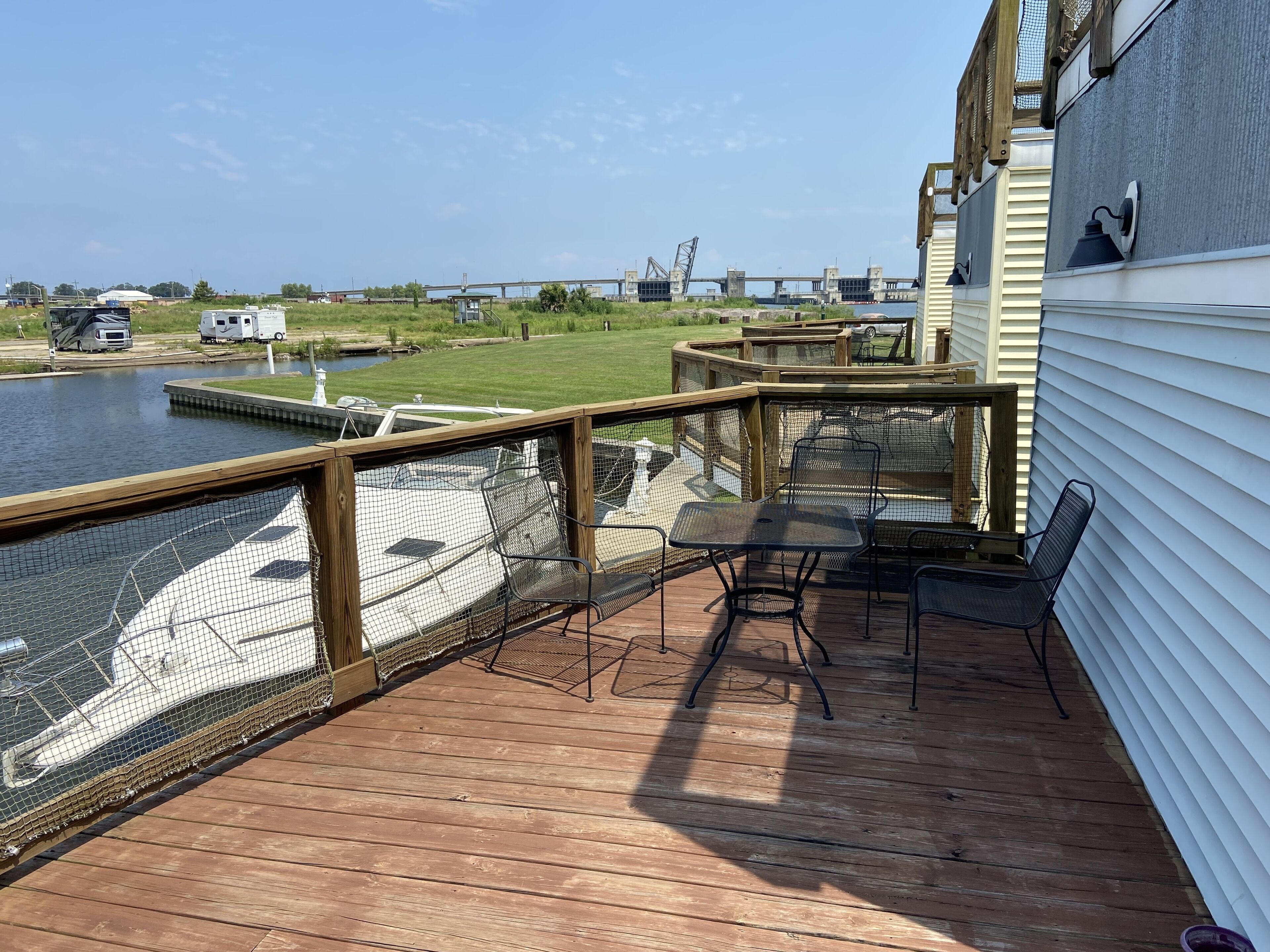 Une terrasse en bois offrant une vue sur une rivière et un pont en arrière-plan.