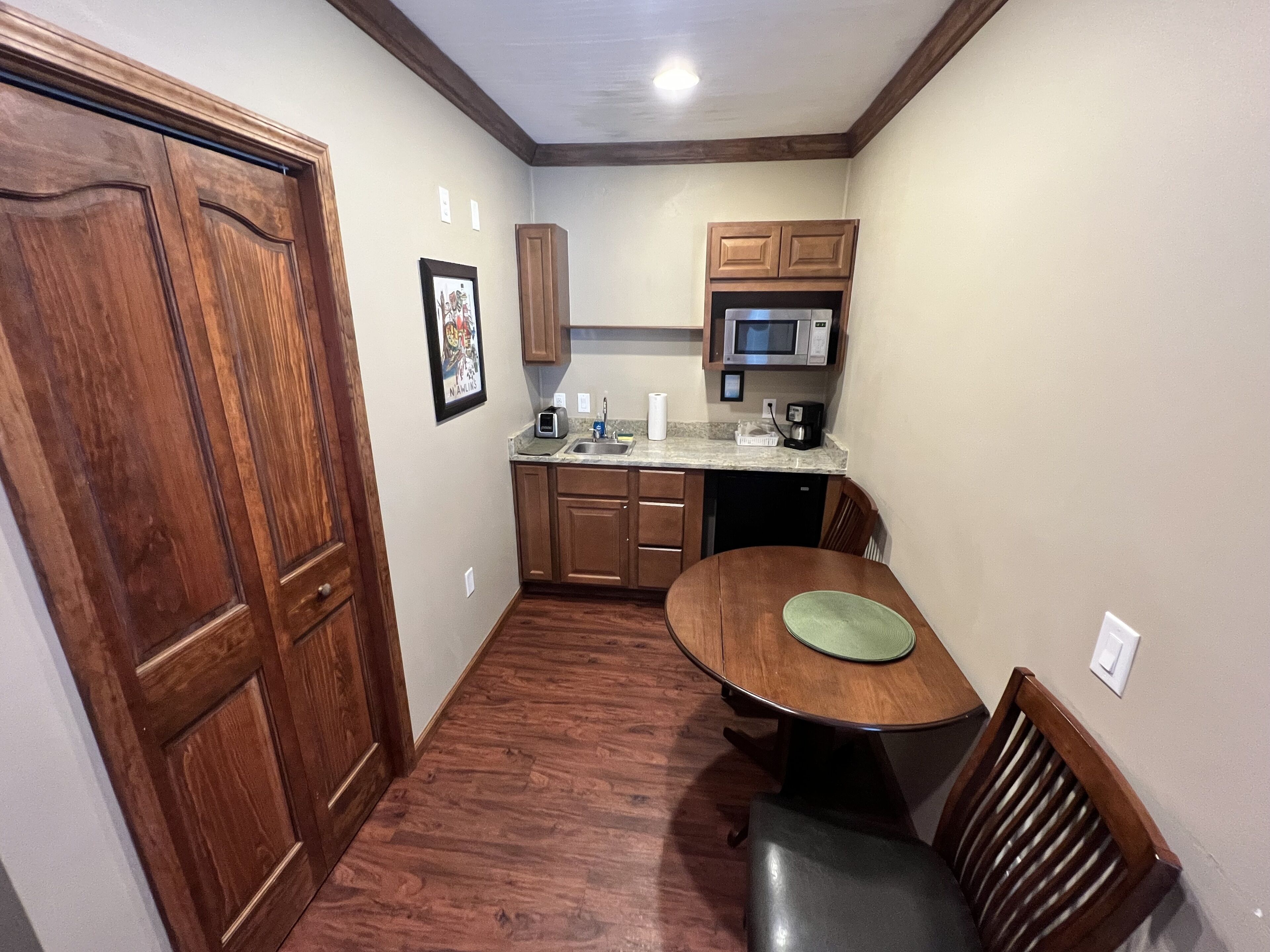 A compact kitchen with wooden cabinets, a microwave, and a dining table with chairs.