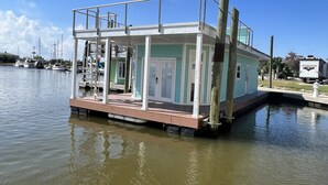 A floating house with a deck and railings, docked in calm water. - New Orleans RV Resort & Marina (New Orleans)
