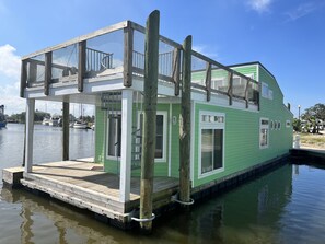A green houseboat with a covered deck and a small staircase leading to the entrance. - New Orleans RV Resort & Marina (New Orleans)