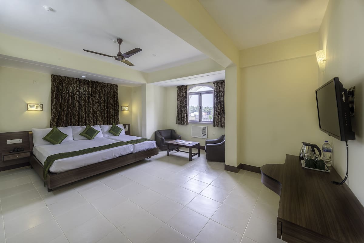 A hotel room with a bed, a desk, a chair, a TV, and a window.