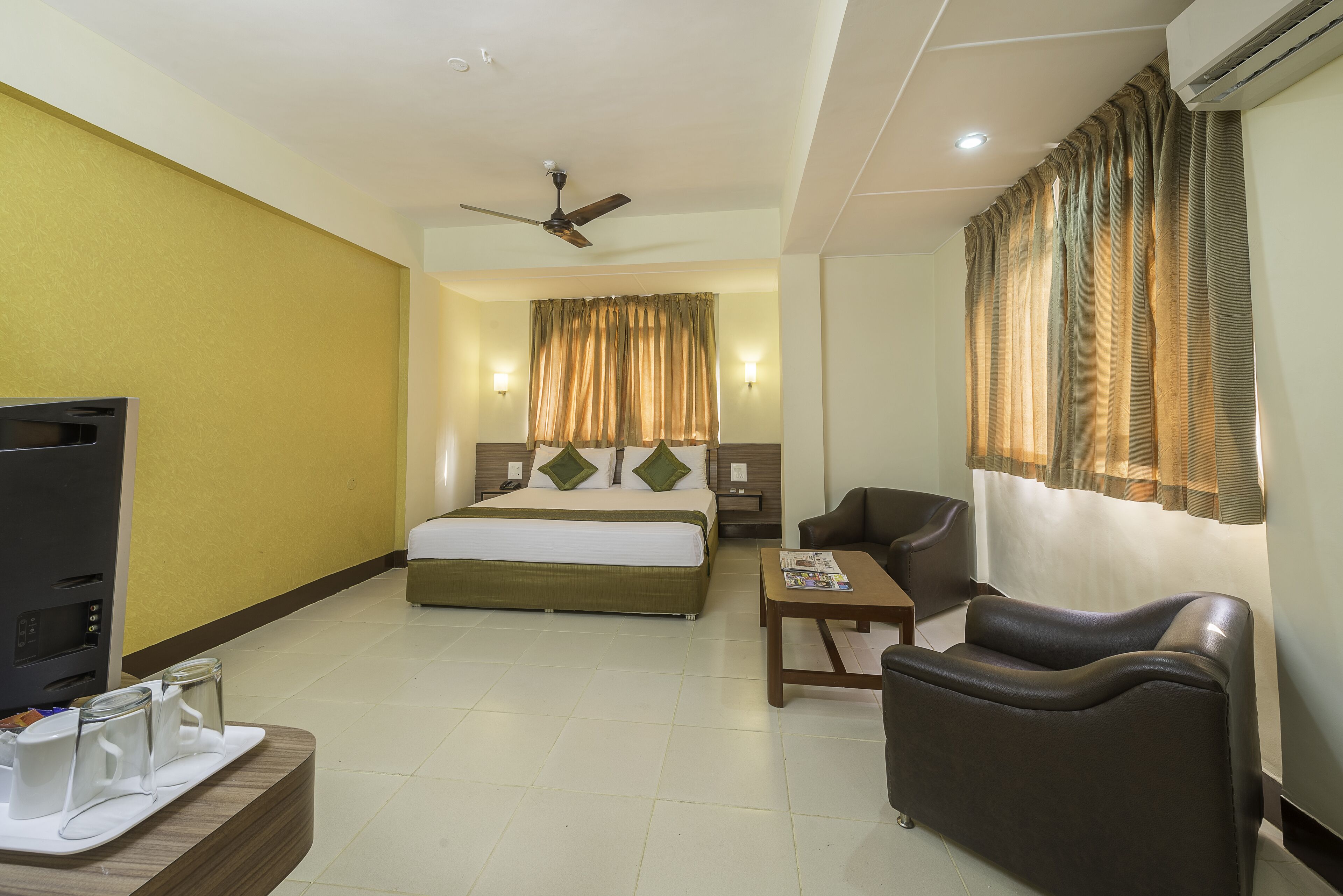 A hotel room with a bed, a TV, a desk, and a chair.