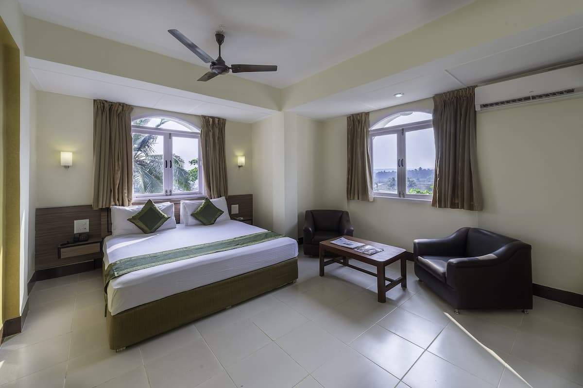A hotel room with a bed, a desk, a chair, and large windows.