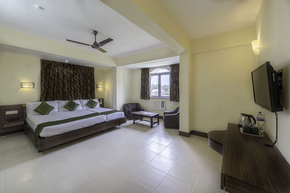 A hotel room with a bed, a desk, a chair, a television, and a window.