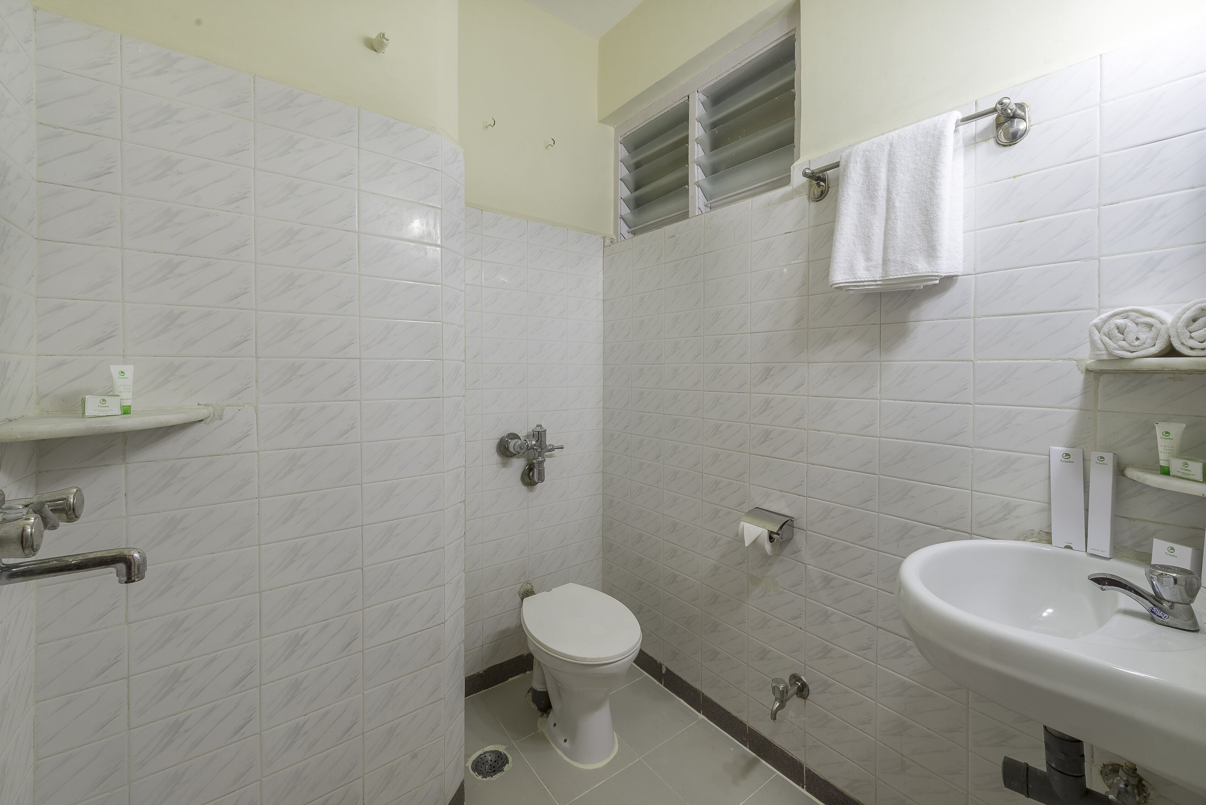 Un baño con inodoro, lavamanos y perchero para toallas.
