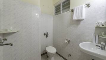 Un baño con inodoro, lavamanos y perchero para toallas.