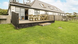 A modern house with a deck, a large window, and a door. - Bwthyn Awel (Holyhead)