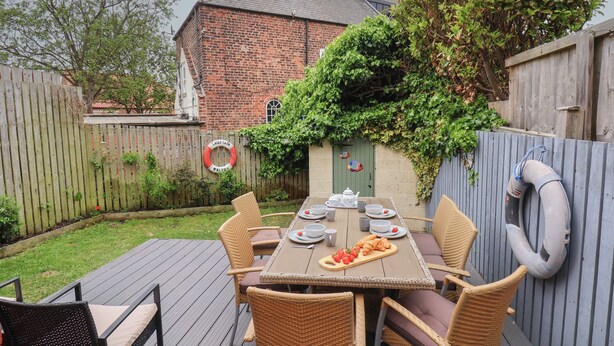 A wooden deck with a table set for four, surrounded by wicker chairs. - Over Esk (Whitby)