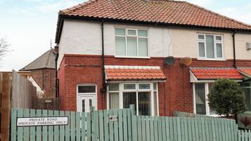 A two-story house with a red-tiled roof, a brick facade, and a green wooden fence with a 'Private Road (Private Parking Only)' sign.