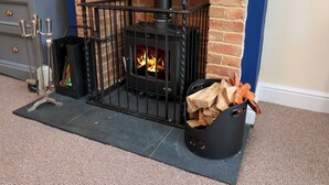 A fireplace with a metal grate, logs, and a decorative metal stand. - Over Esk (Whitby)
