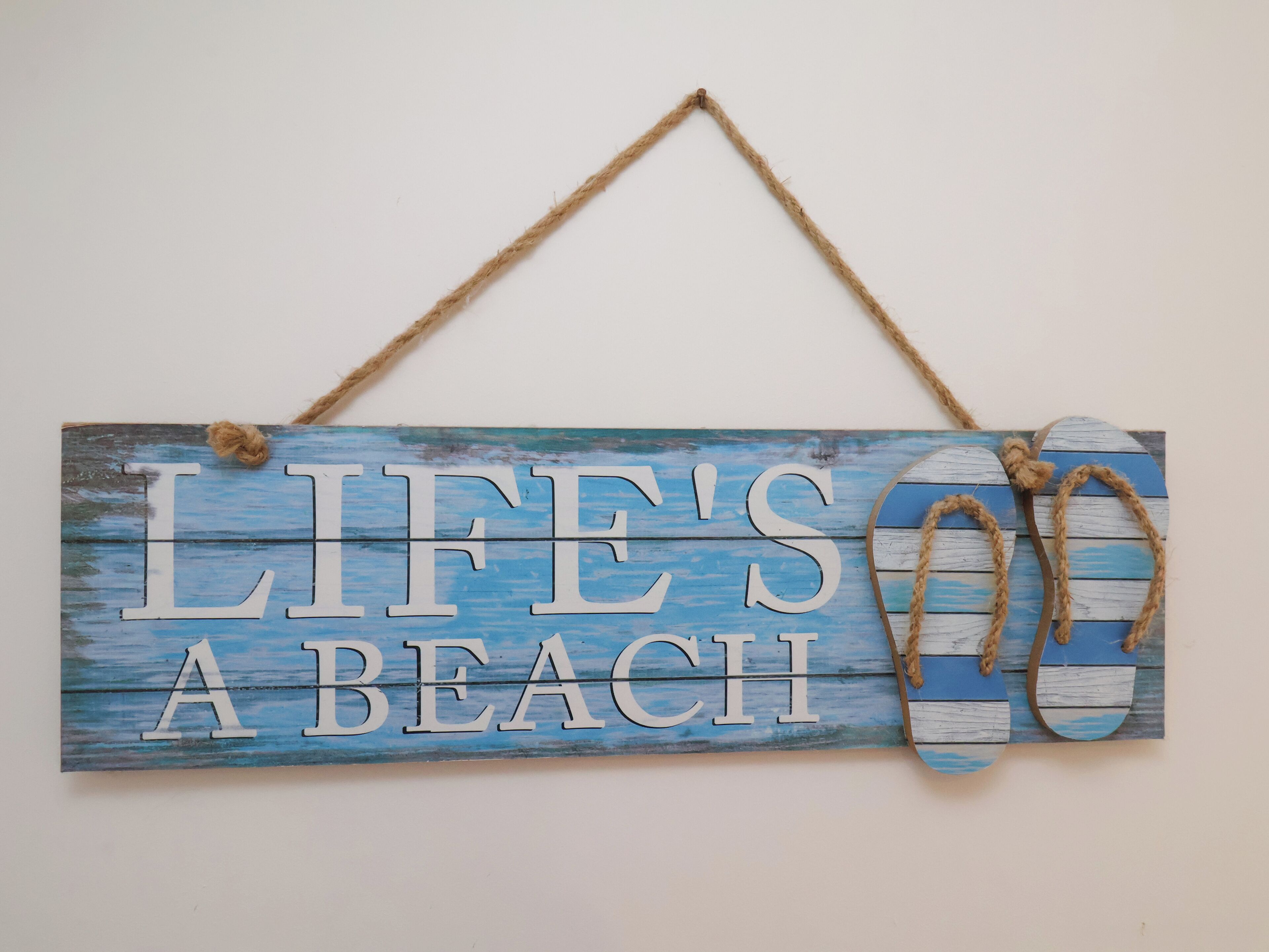 A wooden sign with the text "LIFE'S A BEACH" and a pair of flip-flops.