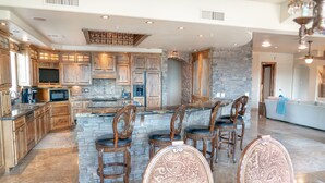 A spacious kitchen with a large island, wooden cabinets, and a stone accent wall. - Enjoy quality time in beautiful Fountain Hills at the coziest home (Fountain Hills)