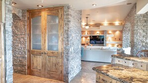 A kitchen with a stone wall, wooden cabinets, and a granite countertop. - Enjoy quality time in beautiful Fountain Hills at the coziest home (Fountain Hills)