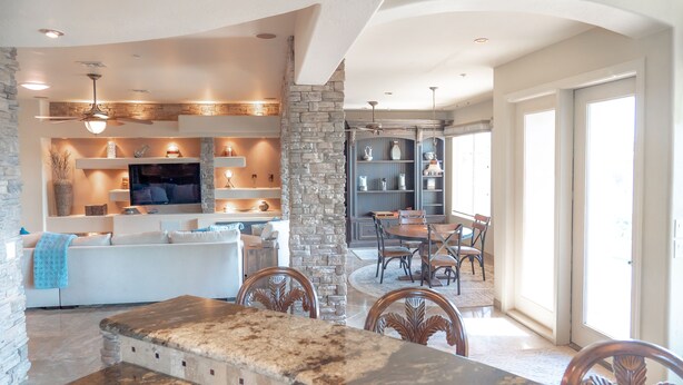 A spacious kitchen with a stone accent wall, modern appliances, and a dining area with wooden chairs and a large table. - Enjoy quality time in beautiful Fountain Hills at the coziest home (Fountain Hills)