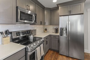 A modern kitchen with stainless steel appliances, wooden cabinets, and a tiled backsplash. - Monthly Special! Location! New Everything 5 Bed Home w/ Hot Tub (Salt Lake City)