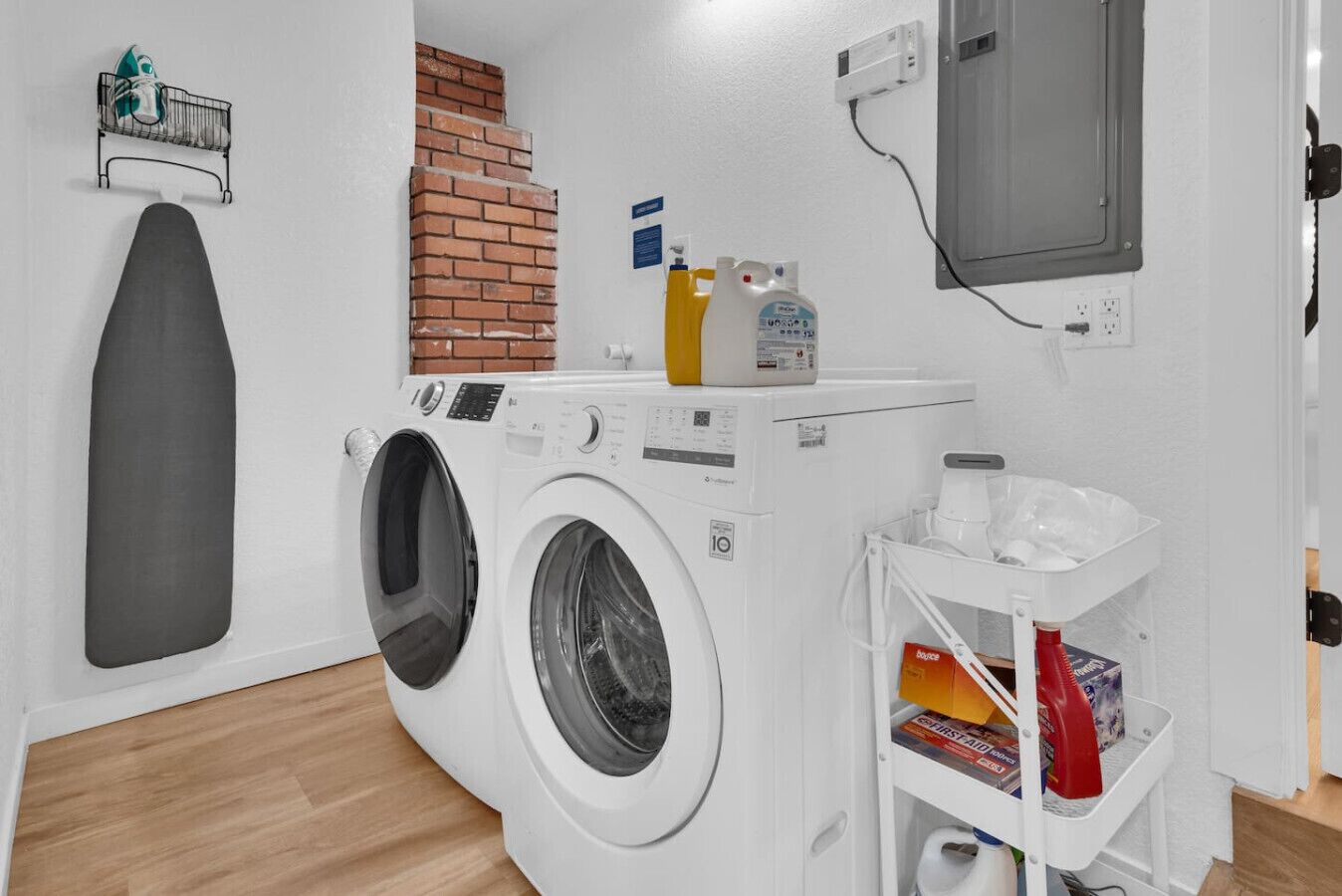 A laundry area with a washing machine, a drying rack, and a shelf with cleaning supplies.