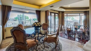 Una habitación amplia con una mesa redonda y sillas, un balcón con barandilla y vistas al exterior.
