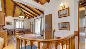 Uma sala de estar ampla com escada de madeira, mesa de jantar e um tapete grande.