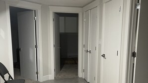 En hall med vita dörrar, en brun matta och en svart stol.