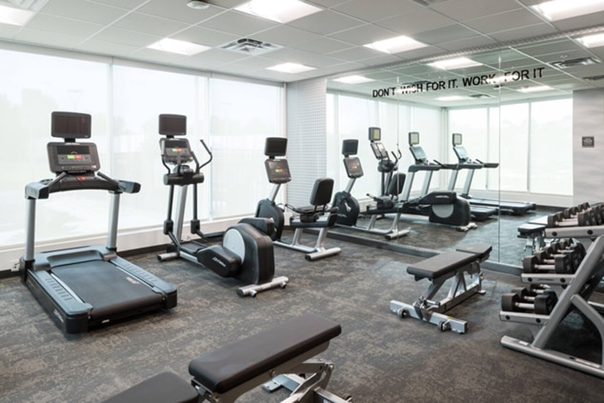 A gym with treadmills, elliptical machines, and weight benches.