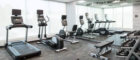 A gym with treadmills, elliptical machines, and weight benches.