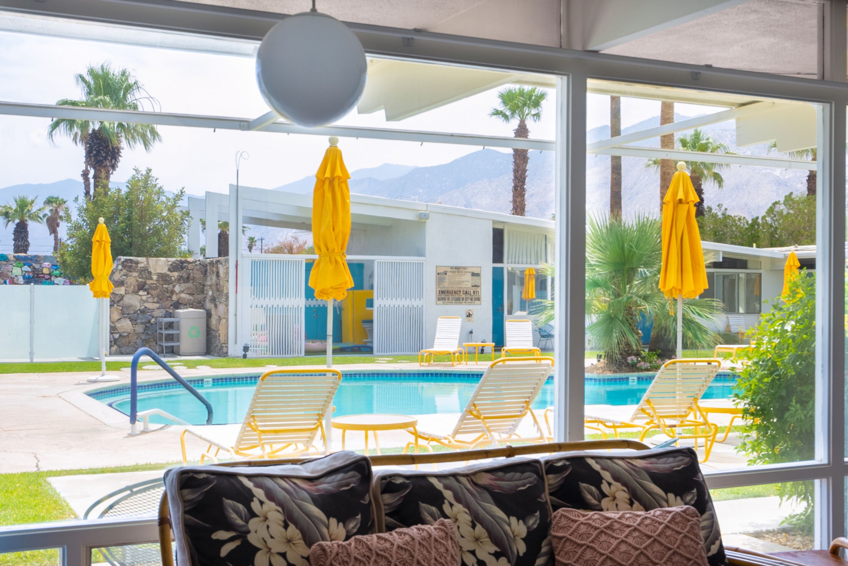 Un espace aménagé au bord de la piscine, avec des parasols jaunes, des chaises longues et une vue sur une chaîne de montagnes.