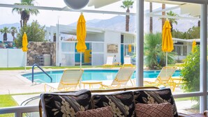 A poolside area with yellow umbrellas, lounge chairs, and a view of a mountain range.