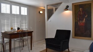 A dining area with a wooden table, clear chairs, and a painting on the wall. - Matchbox is a delightful dog-friendly cottage in Winchelsea, East Sussex (Winchelsea)